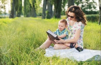 Mother with curly hairstyle reading fairy tales for cute  baby