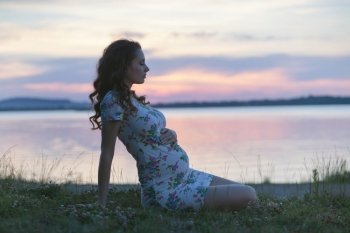 Calm pregnant lady sitting on the lakeside