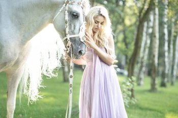 Blond cute woman with a white  horse