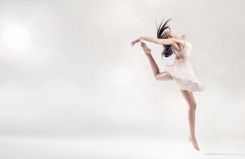Pretty female ballet dancer in hard jump figure