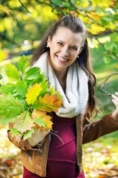 Pretty mother holding bouquet of autumn leaves