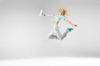 Woman jumping and holding a paintroller