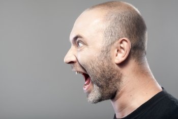 portrait of angry man screaming isolated on gray background with copyspace