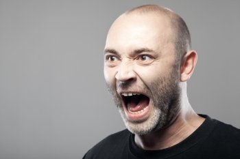 portrait of angry man sreaming isolated on gray background with copyspace