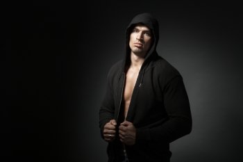 strong man wearing hoodie isolated on black background with copyspace