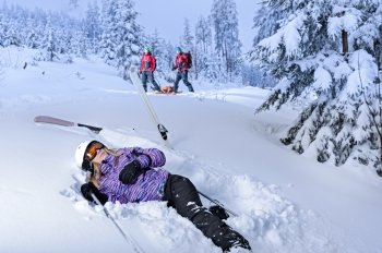 Skier after accident waiting for mountain rescue lying in snow