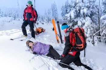 Rescue ski patrol help injured woman skier lying in snow
