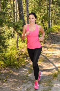 Athlete woman running through forest training in the countryside