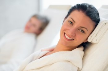 Smiling woman resting at beauty spa room friend in background