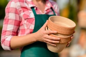 Two clay pots held by garden center worker close-up sunny
