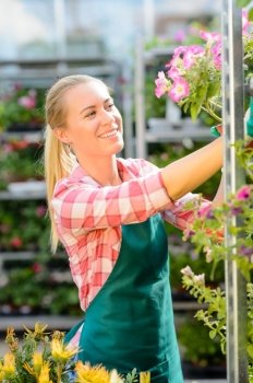 Garden center woman working with potted flowers smiling sunny day