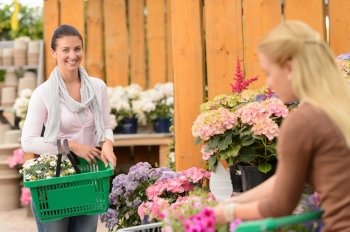 Woman buying flowers in garden center carry shopping basket smiling