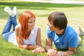Teenage couple lying on grass looking at each other sunny