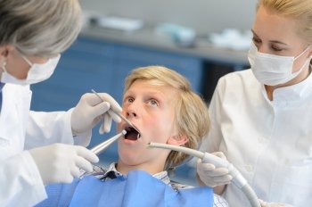 Dentist and assistant with scared teenage patient open mouth checkup