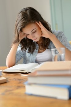 Student teenage girl concentrate reading book home holding her head