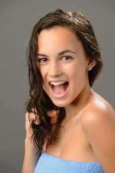 Cheerful teenage girl pulling wet hair care brunette on gray background