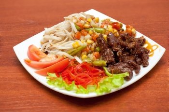 chinese noodles with roasted meat and vegetables. plate of chinese noodles with roasted meat and vegetables
