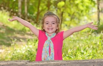 little girl enjoying and raising her hands in park