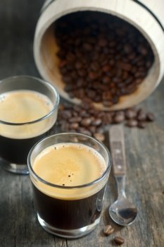 two cups of coffee and coffee beans on old wooden background