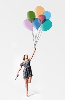 imagination. young woman is flying away with drawn balloons. imagination