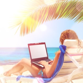   surfing on the beach. young caucasian woman is surfing internet with the notebook at sunset beach. Laptop display is cut with clipping path