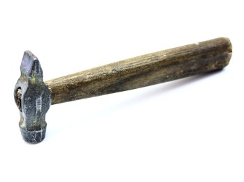 The old metal hammer with the wooden handle lies on a white background