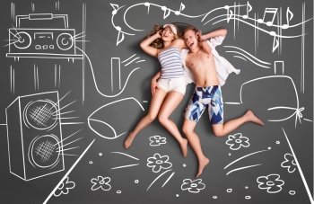 Love story concept of a romantic couple lying in bed, sharing headphones, and listening to the music against chalk drawings background of a bedroom with acoustic system.