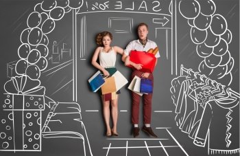 Love story concept of a romantic couple on shopping against chalk drawings background. Young couple with shopping bags entering a shopping mall during sales.