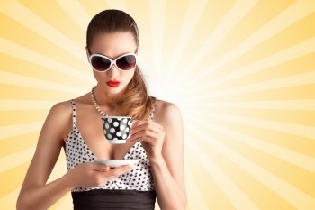 Creative vintage photo of a beautiful pin-up girl in a polka dot bikini and sunglasses, drinking tea or coffee on colorful abstract cartoon style background.