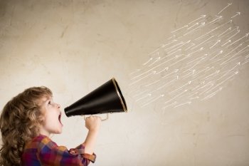 Kid shouting through vintage megaphone. Communication concept.