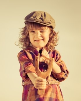 Funny kid shooting wooden slingshot. Retro toned image