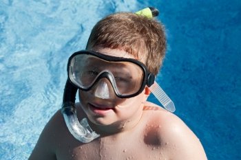 Funny boy with diving goggles and snorkel swimming in the water