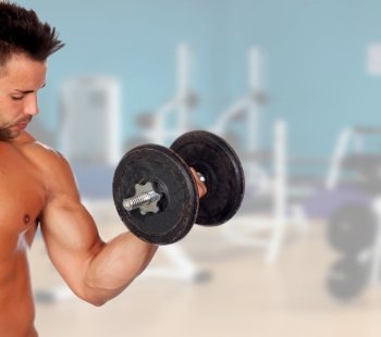 Muscled guy lifting weights in the gym