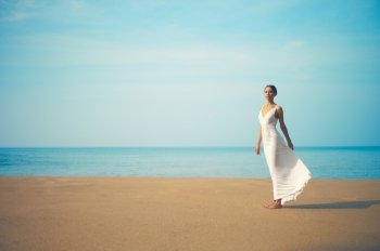 Young lady in white dress jumping on the beach