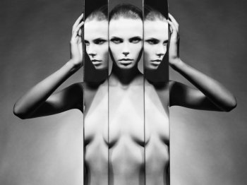 Fashion studio portrait of nude elegant woman and mirrors on black background