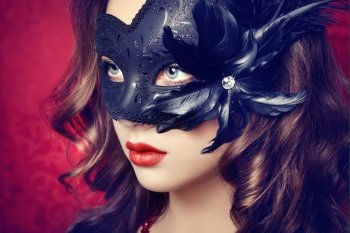 Beautiful young woman in black mysterious  Venetian mask. Fashion photo