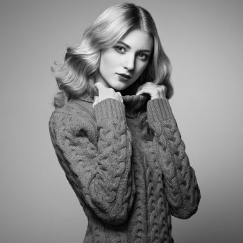 Fashion photo of beautiful woman in sweater. Curly hairstyle. Make-up. Black and white
