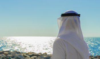 Man in Arab dress looks at the sea