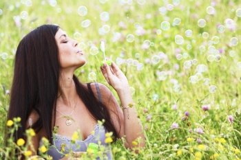 Woman blows soap bubbles on flower field