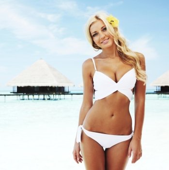 Sexy woman in bikini on beach on sea and villa background