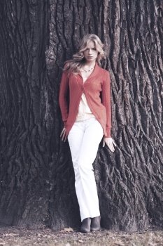 Beautiful blond woman posing on tree trunk background