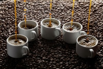 Pouring coffee into five cups on coffee beans