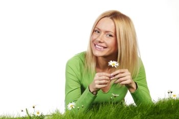 Beautiful young blonde woman lying on grass with chamomile flowers, isolated on white background