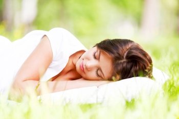 Beautiful young woman sleeping on grass outdoors. Woman sleeping on grass