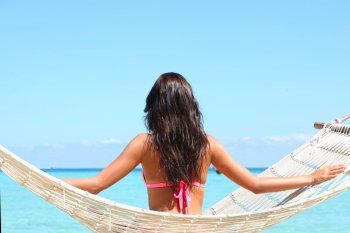 Woman in hummock. Young woman in bikini swinging  in hummock on tropical beach