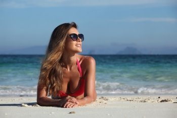 Woman in bikini at tropical beach. Woman in bikini and sunglasses laying at tropical beach