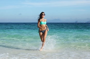 Woman run on beach. Beautiful fit woman in bikni run on tropical beach