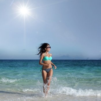 Woman in bikini run to beach. Young attractive woman in bikini run from sea to beach