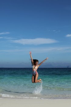 Happy woman on beach. Beautiful happy woman in bikni jump on tropical beach