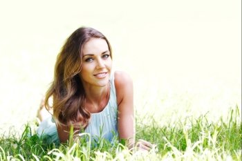 young woman in blue dress lying on grass. beautiful young woman in blue dress lying on grass